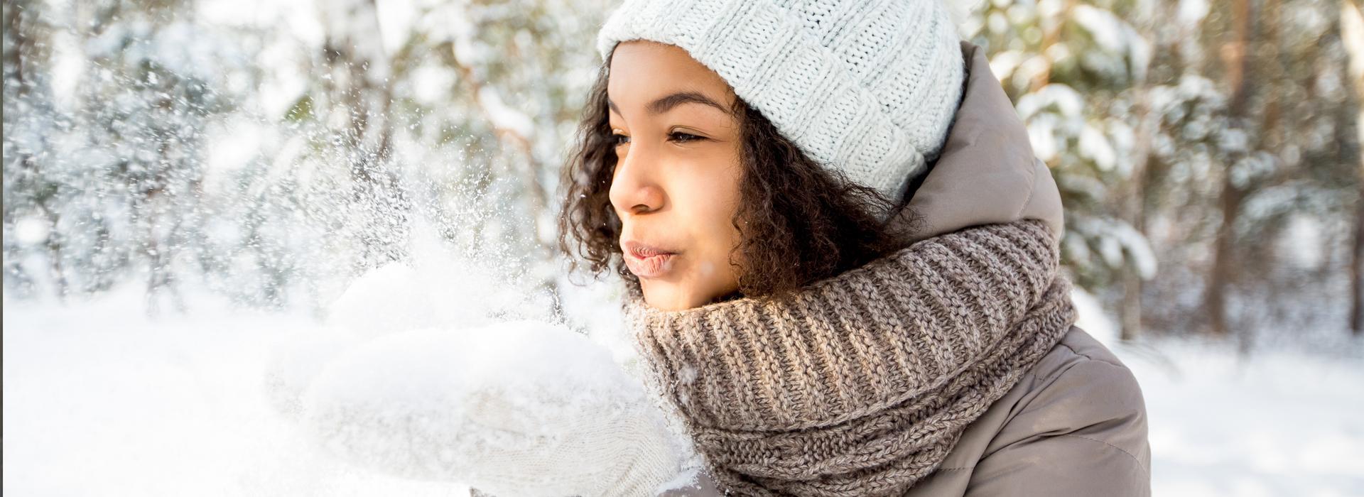 a-women-playing-in-the-snow-and-blowing-snow-from-her-hands