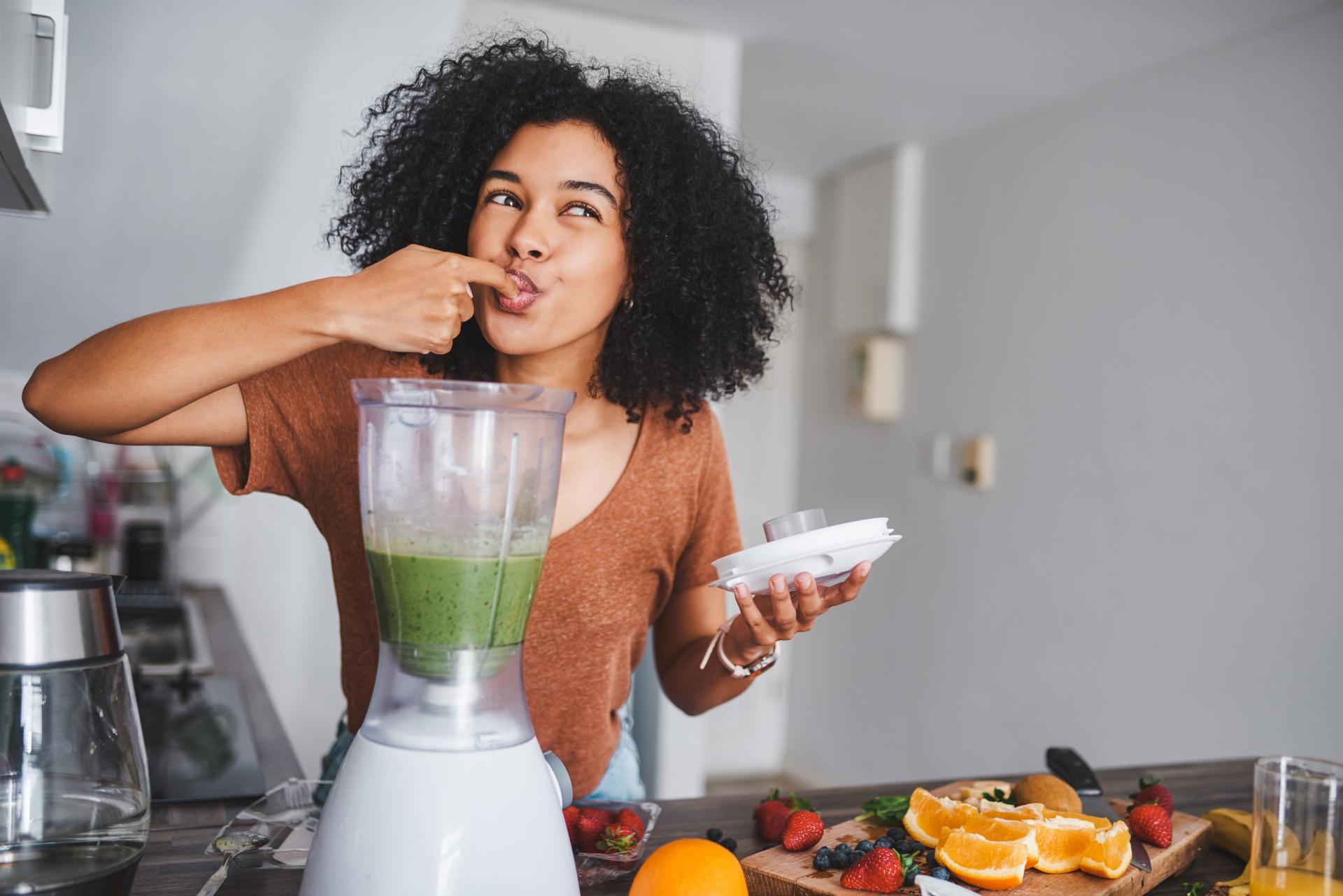 Women making a healthy fruit smoothie and tasting it