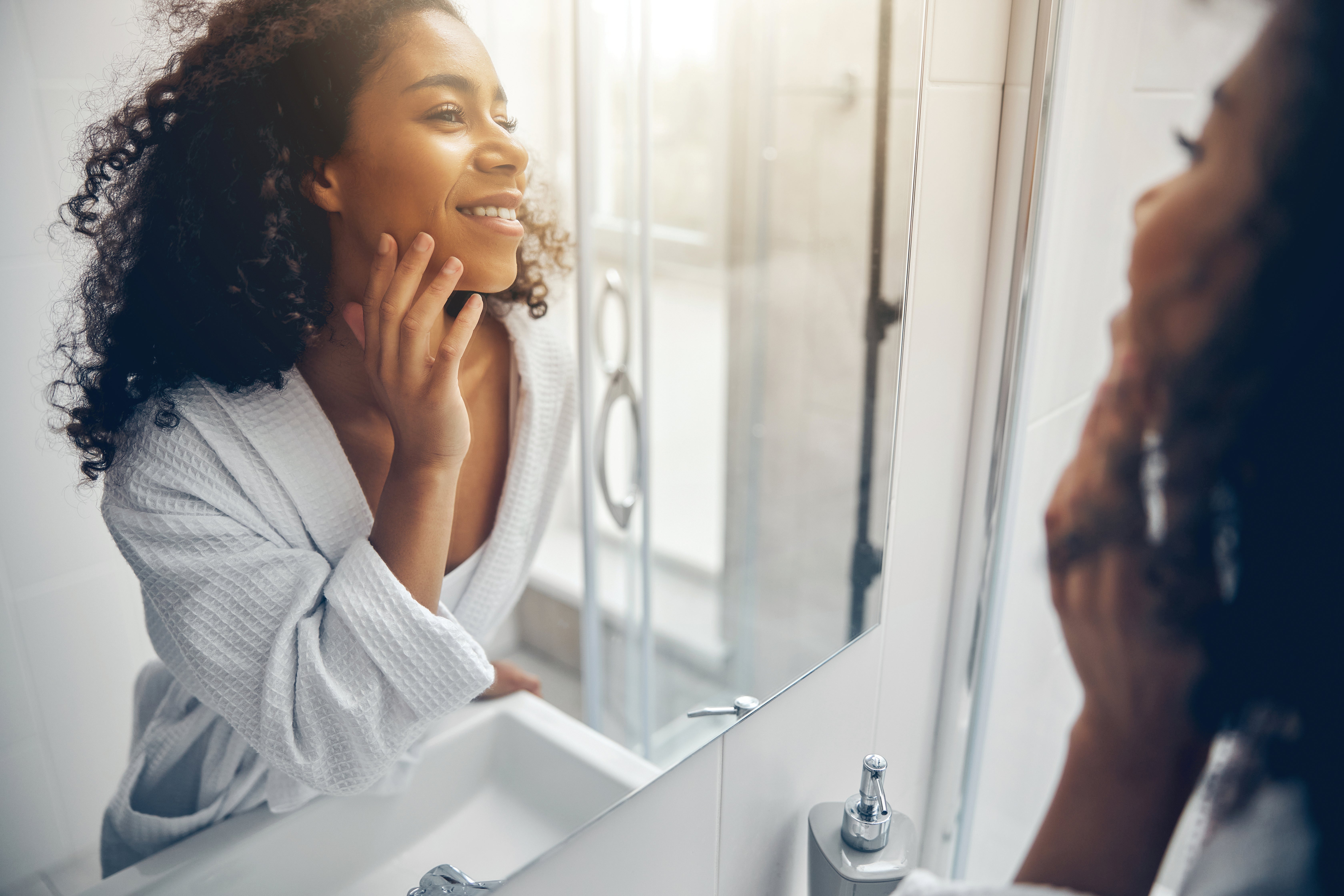 Women applying her skincare in the mirror and smiling