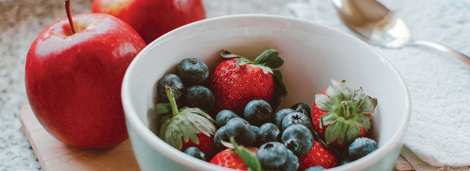Les fruits Fraises et bleuets dans un bol avec des pommes rouges à côté.