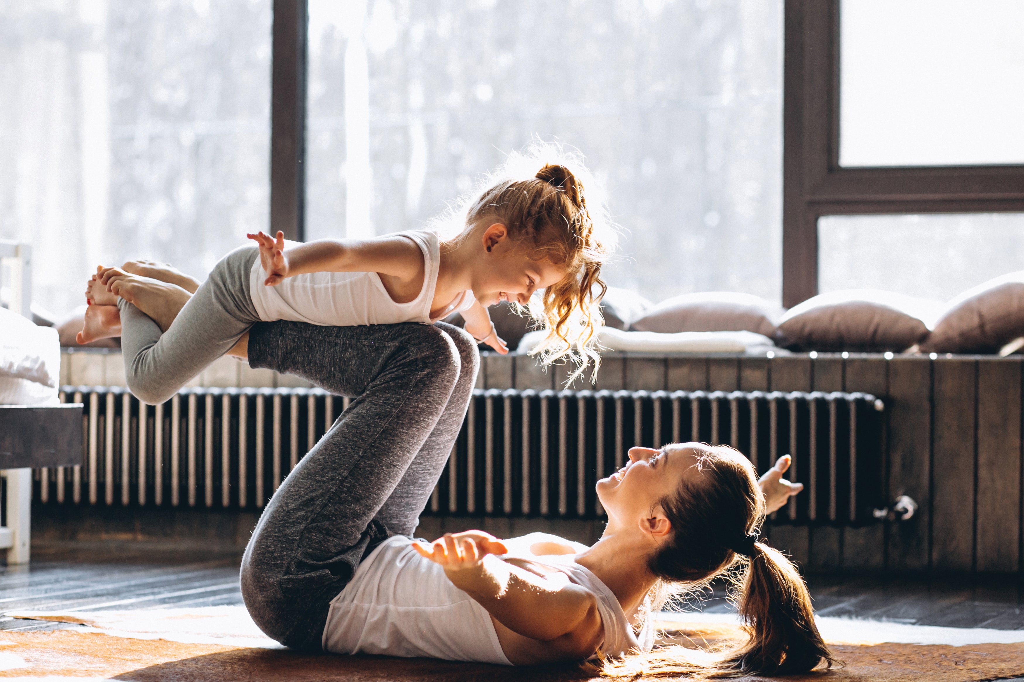 Women balancing daughter on her legs and playing 