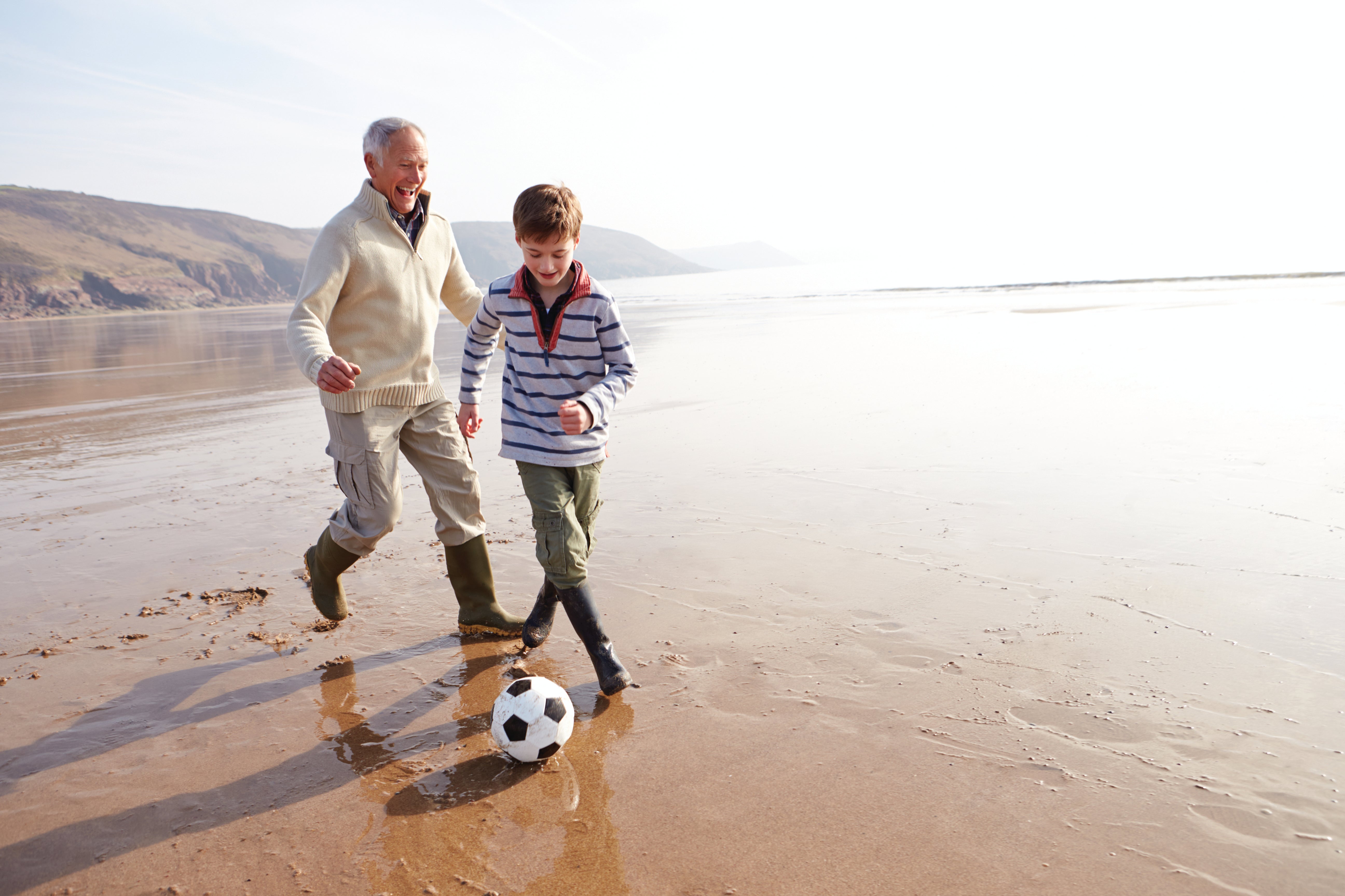 Grandpa playing soccer with grandson at the beach