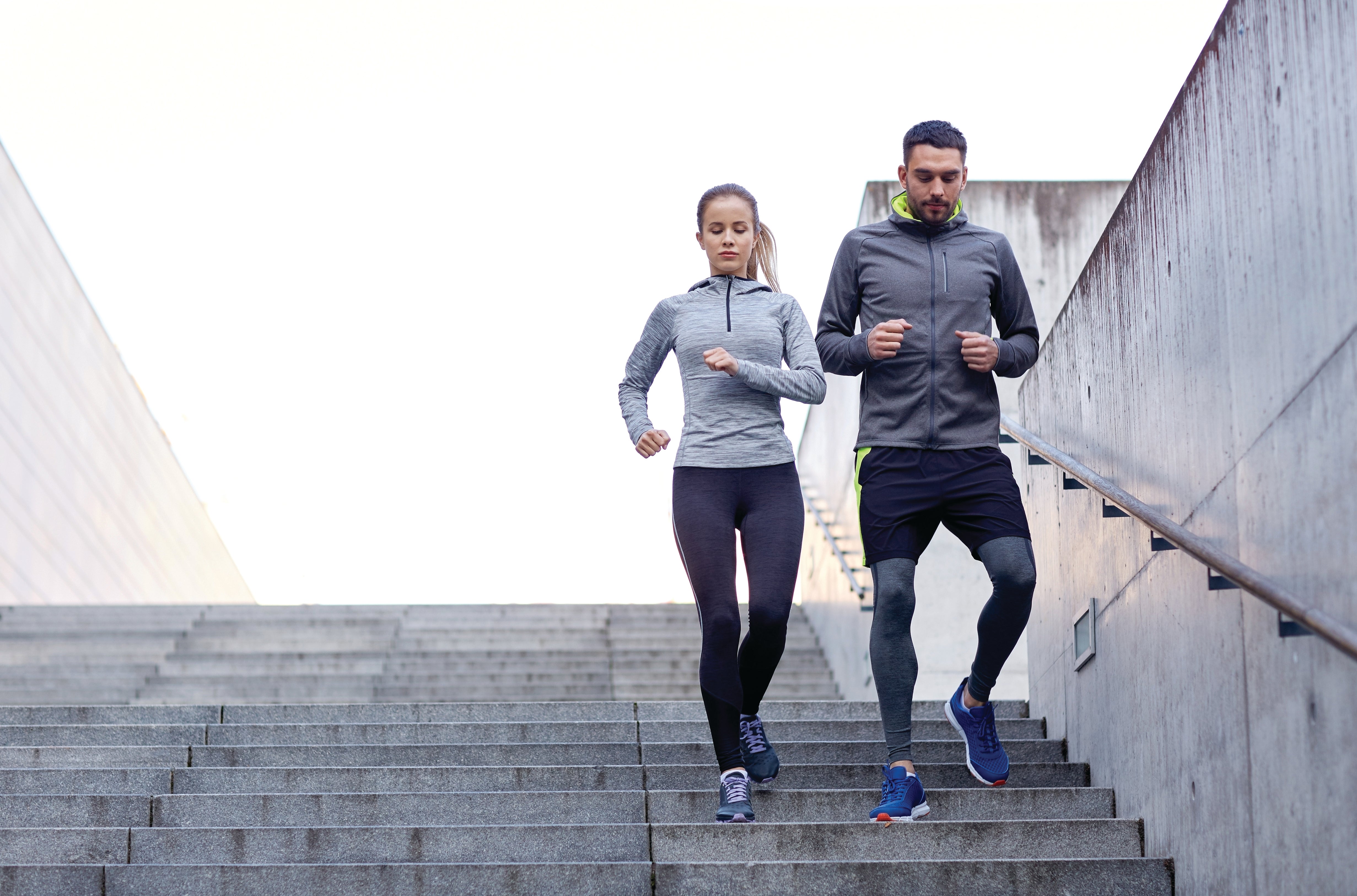 Man and women running down stairs exercising outdoors 