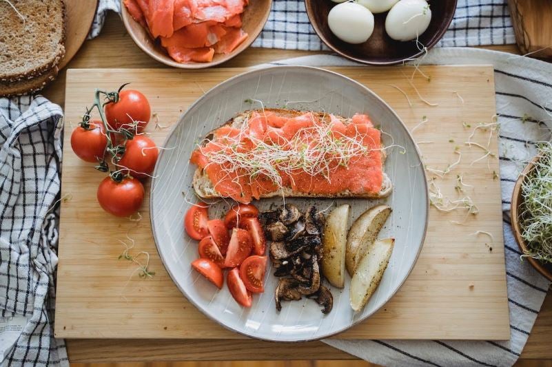 Healthy meal with salmon on toast, tomatoes, mushrooms, potatoes and eggs