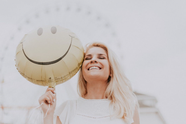 Women smiling holding a smiley face balloon 