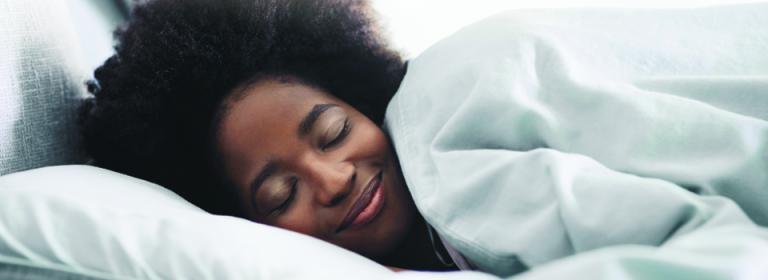 a-women-sleeping-and-smiling-in-bed