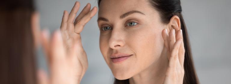 Women applying skincare in the mirror