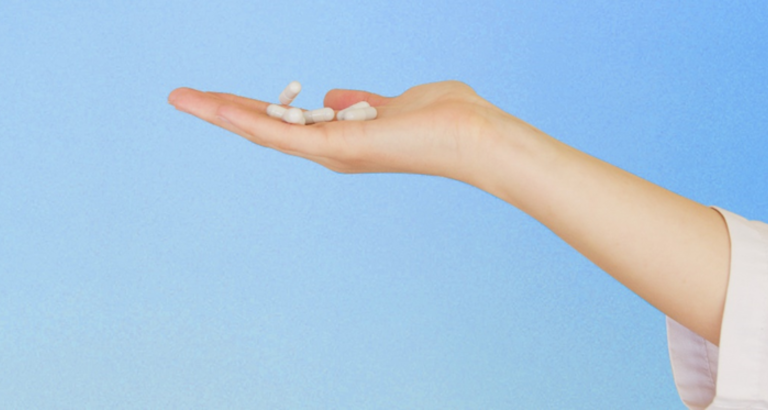 Holding vitamin supplements on the palm of a hand
