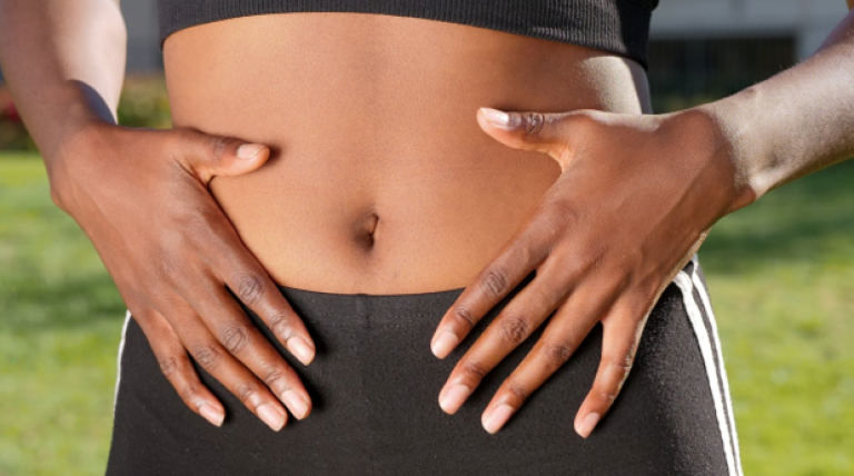 Women in sports clothing and holding her hands on her stomach.