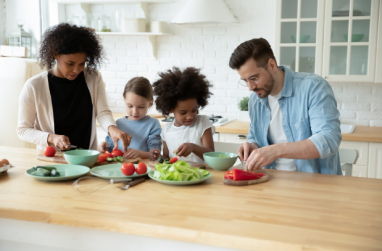 Un mari et une femme préparent un déjeuner sain avec leurs enfants dans la cuisine.