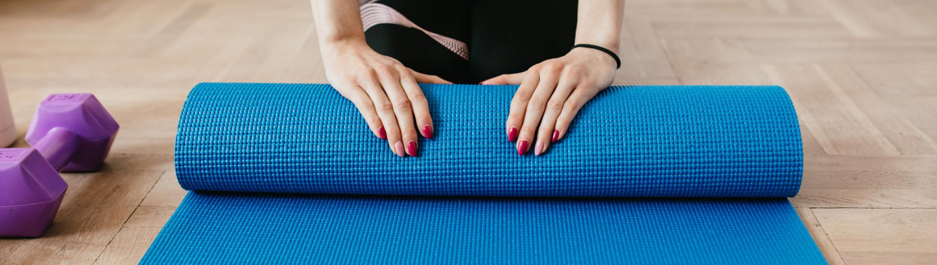 Women rolling up yoga mat after finishing a yoga class