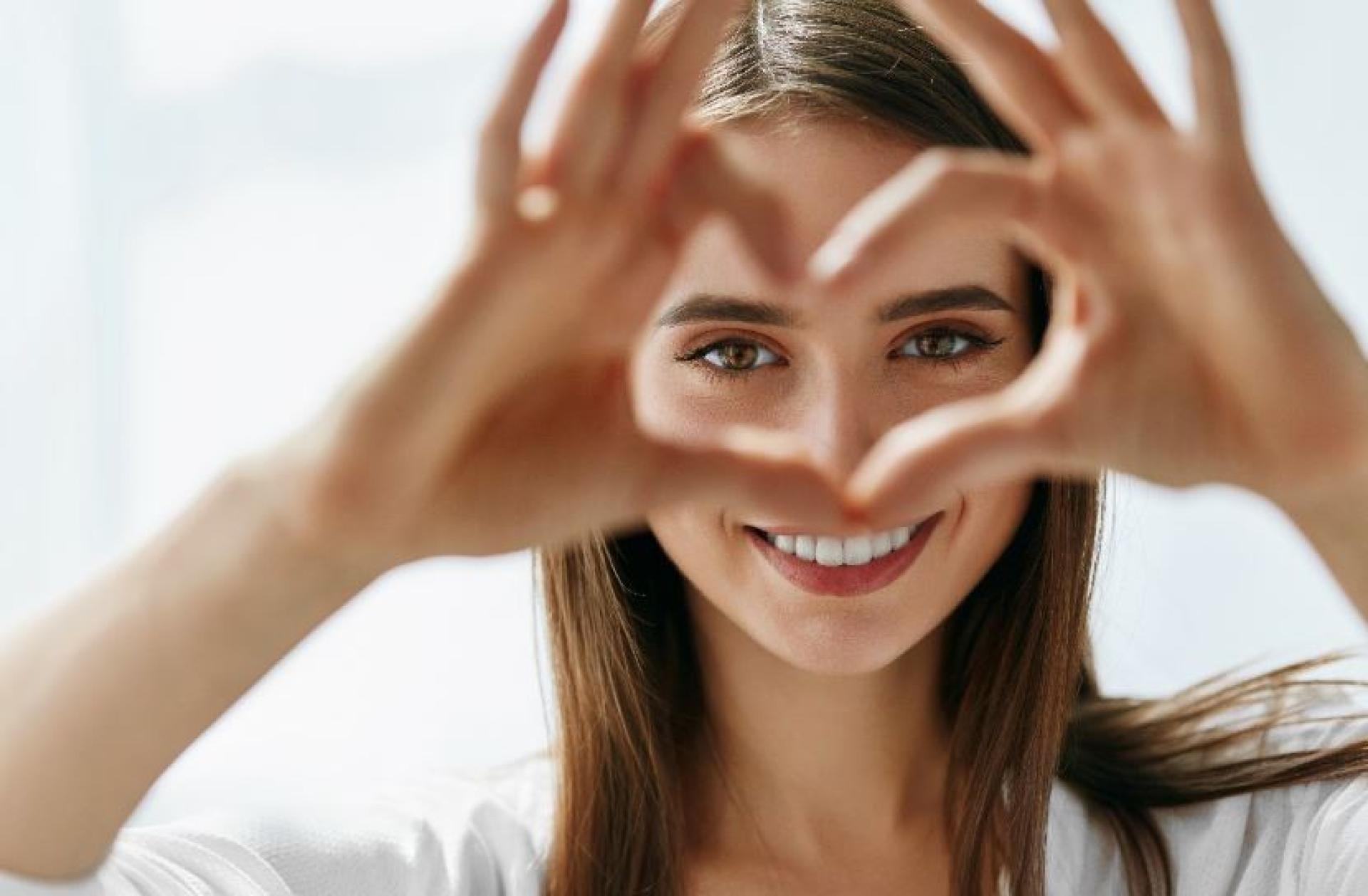 Women smiling and forming a heart with her hands