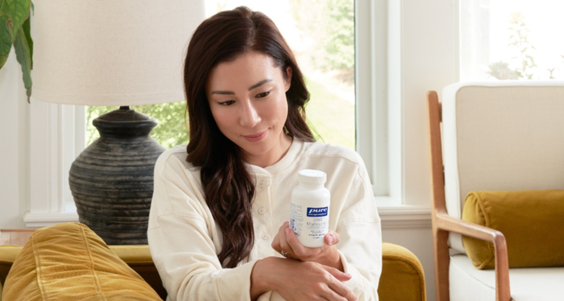 Une femme tenant une bouteille de supplément Pure Encapsulations